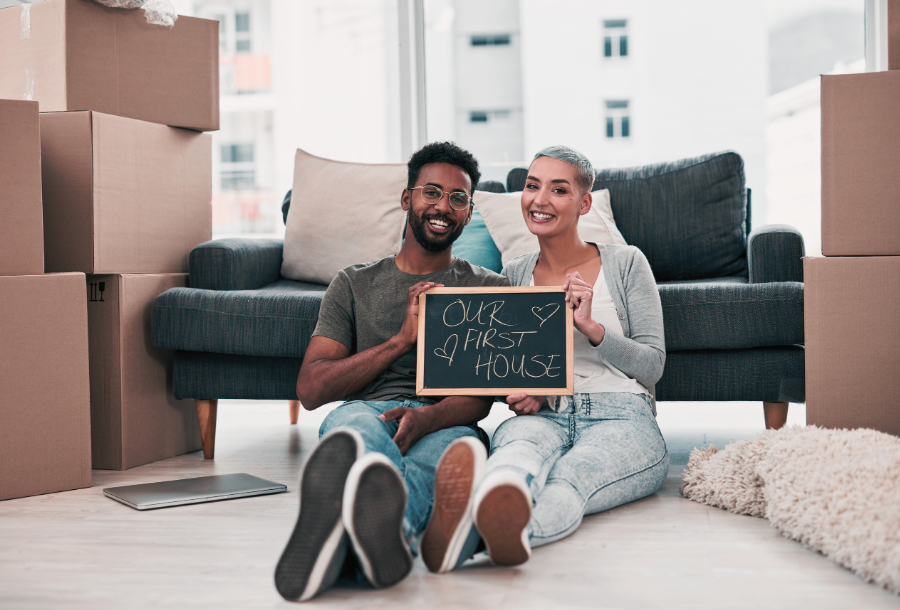 First-Time Buyers - Couple holding a sign our first house